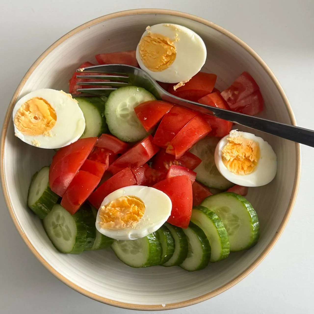 Тарелка с огурцами, помидорами и варёными яйцами как пример простого приёма пищи после похудения