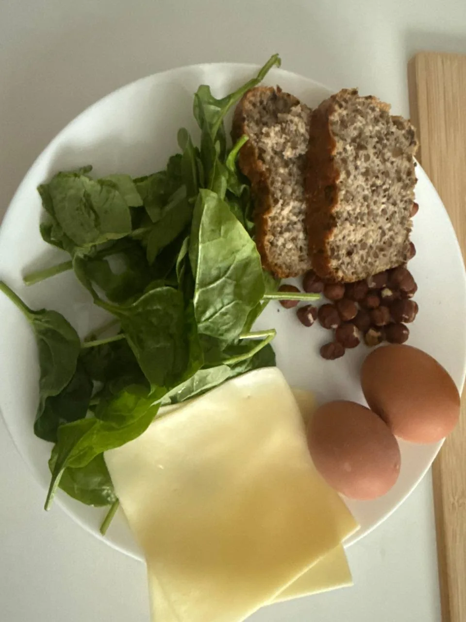 Тарелка с цельнозерновым хлебом, яйцами, сыром, орехами и зеленью как пример более полезного приема пищи после 40 лет