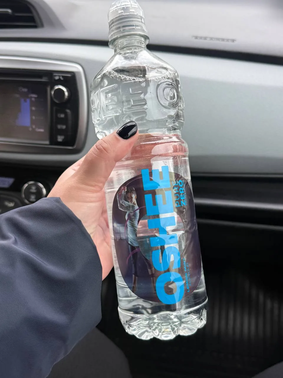 Рука с бутылкой воды в салоне автомобиля, крупный план