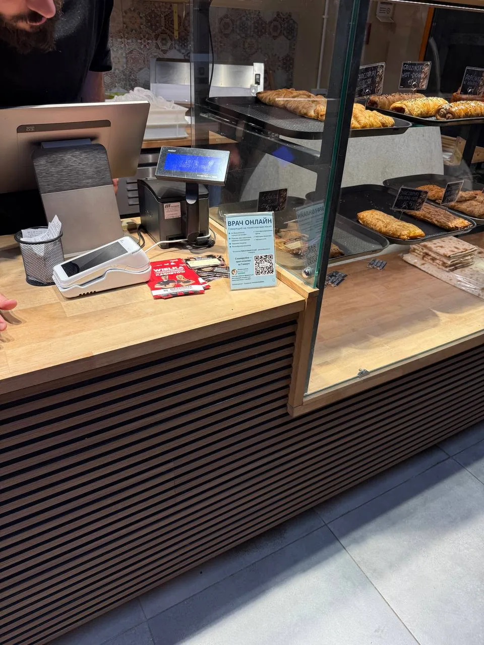 витрина пекарни с выпечкой и кассой на прилавке